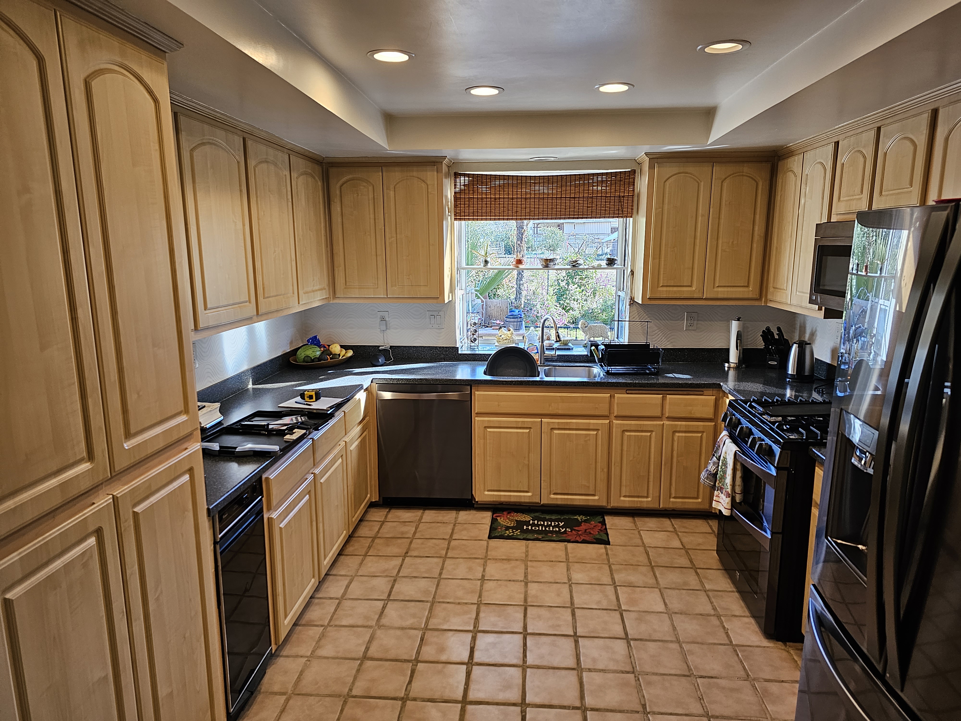 Old kitchen wide shot — dated oak cabinets, tile floor, cluttered