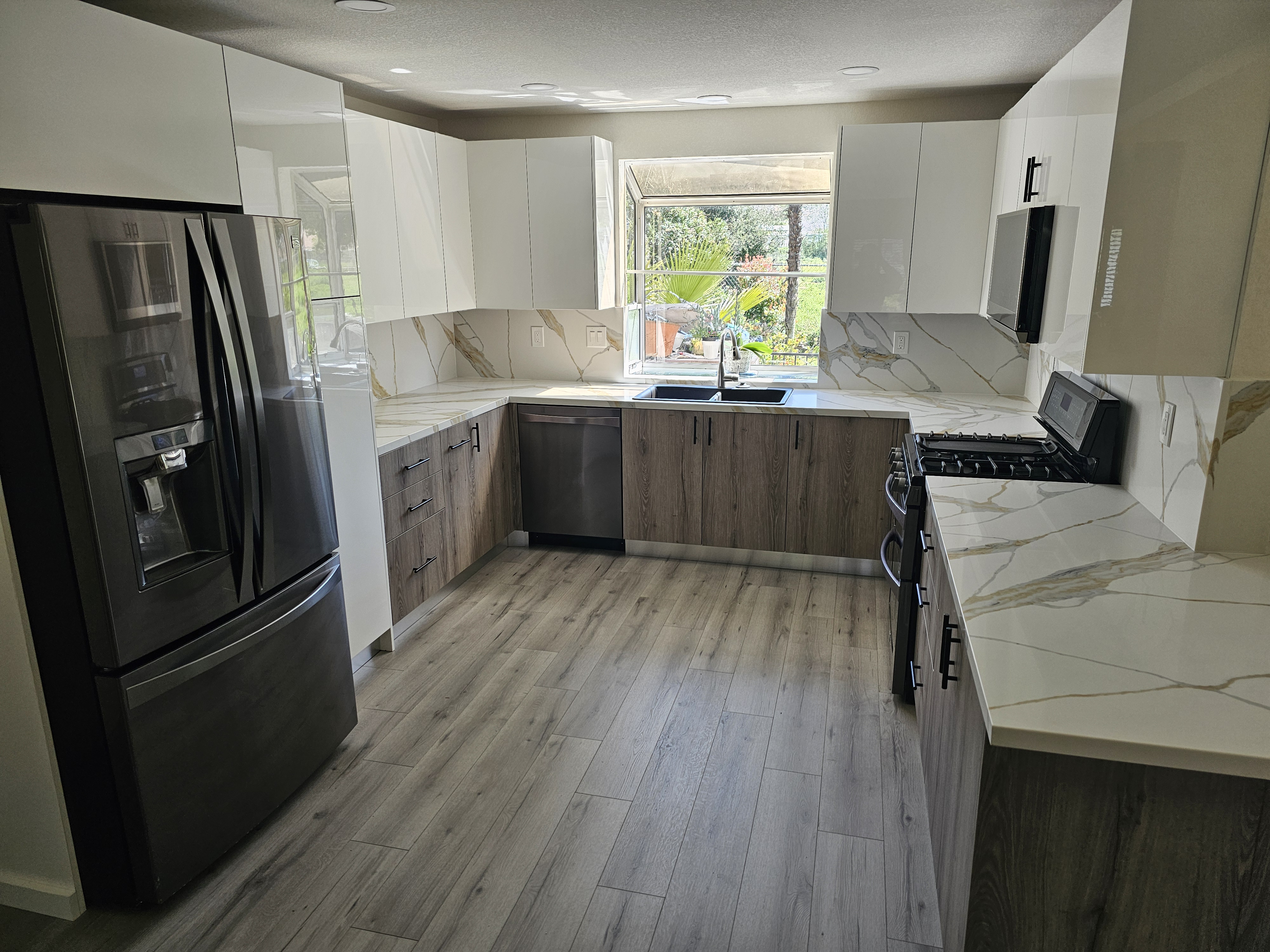 Same kitchen after remodel — open concept, island, pendant lights, calacatta quartz