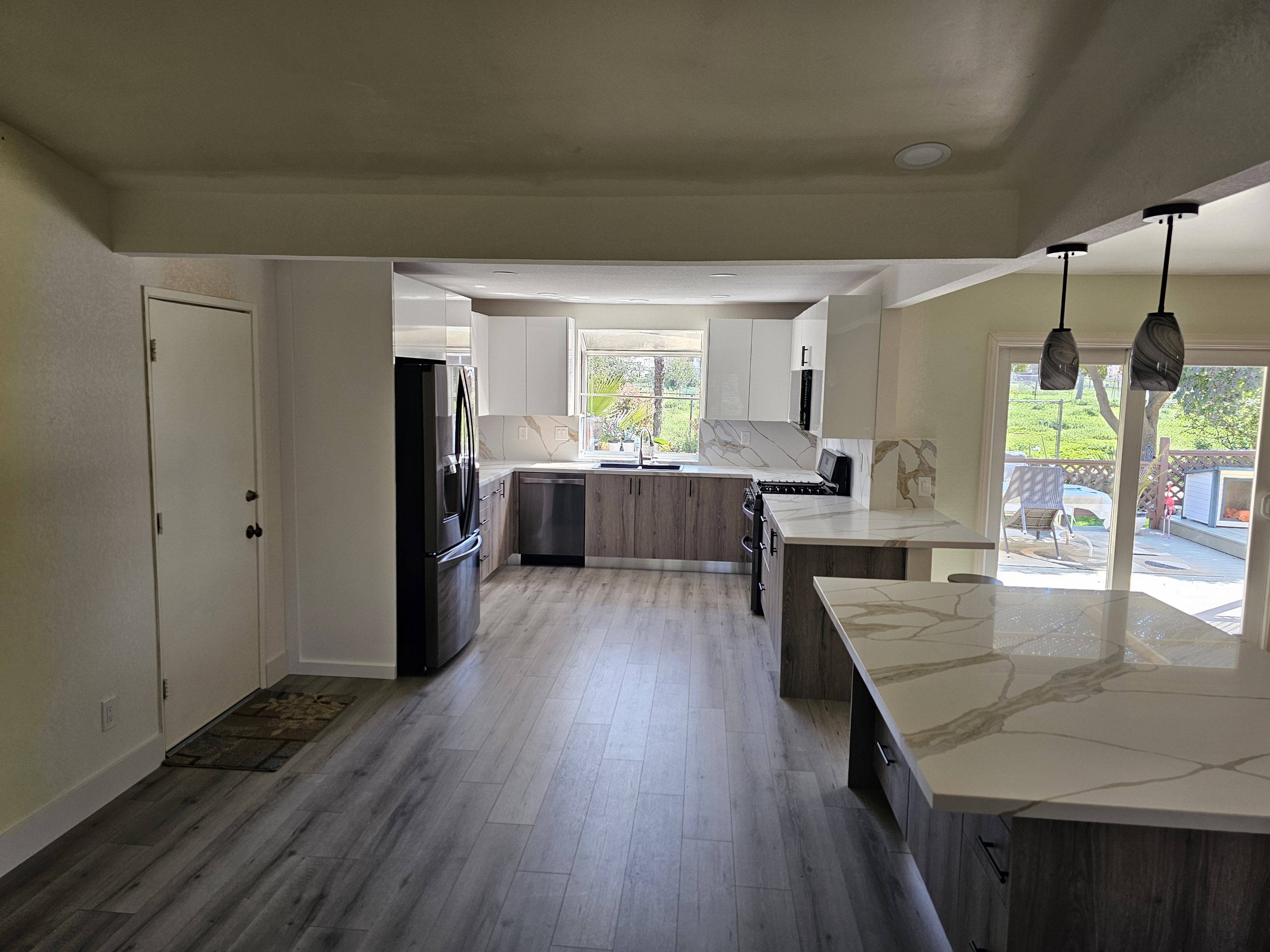 Open kitchen from entry showing two-tone cabinets and calacatta quartz