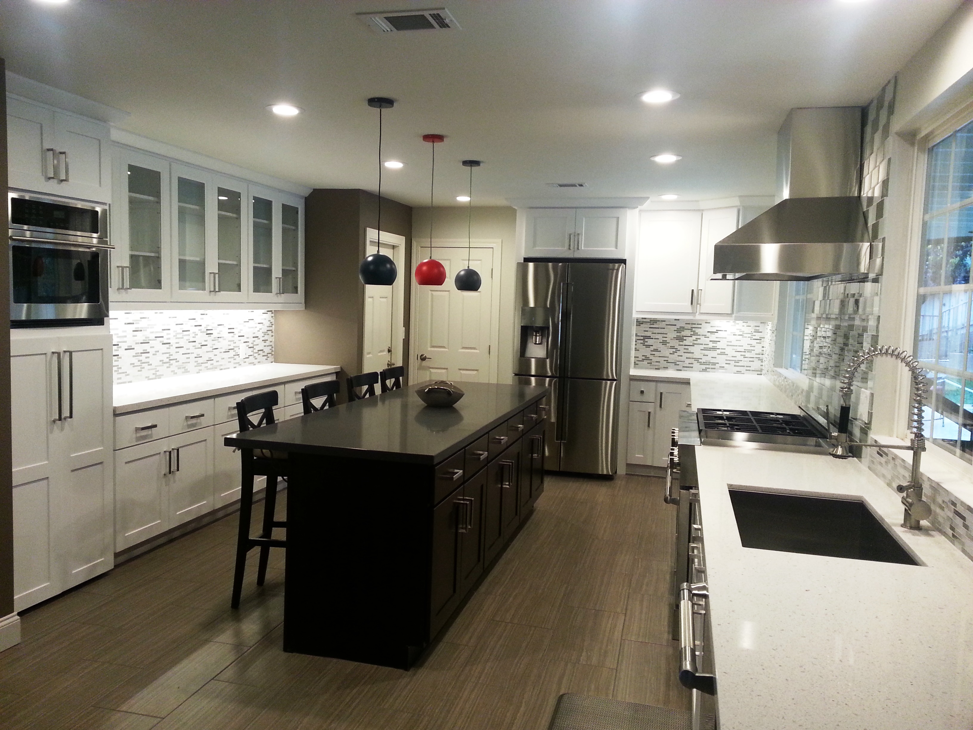 Contemporary kitchen with two-tone cabinets, dark island with seating, and mosaic backsplash