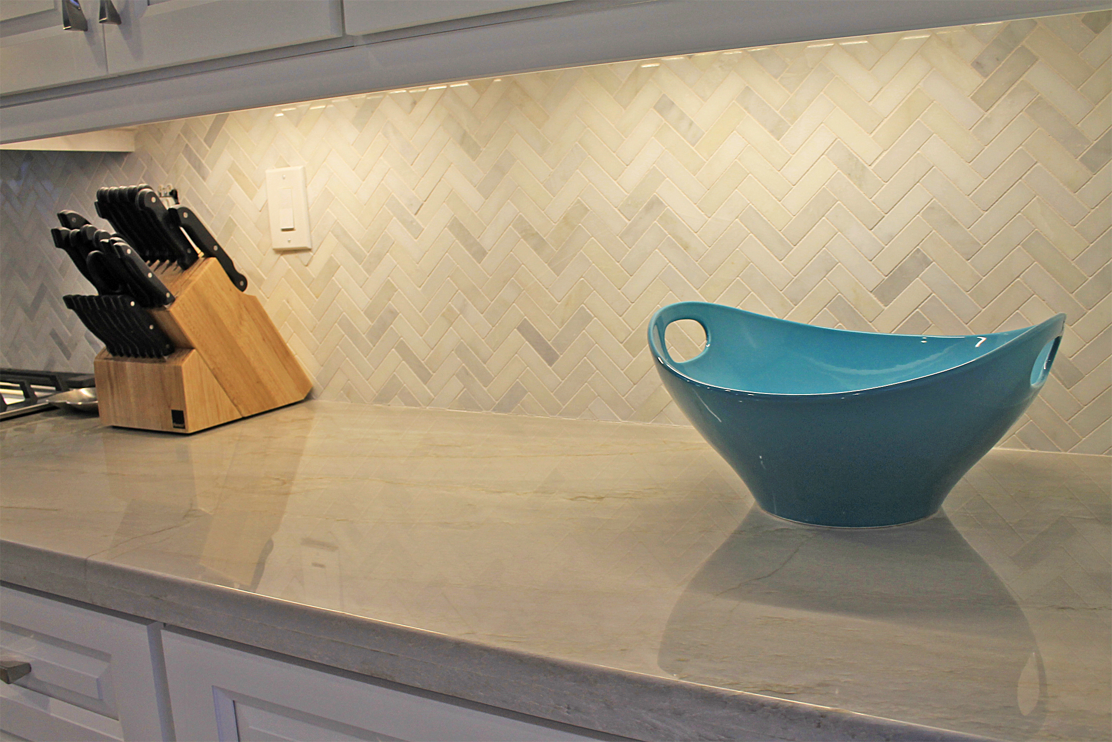 Detail of herringbone marble backsplash and polished stone countertop showing craftsmanship